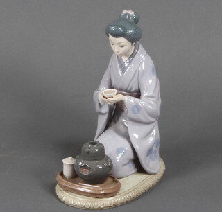 A Lladro figure of a kneeling Japanese lady taking tea 22cm 