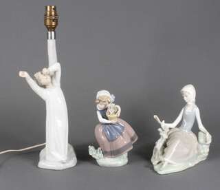 A Lladro figure of a lady sitting before a dove 17cm, ditto of a girl holding a pot of flowers 16.5cm and a Nao table lamp the base with a yawning boy 40cm 