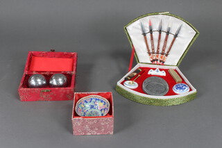 A Chinese porcelain tea bowl decorated flowers, a cased writing set and musical balls boxed