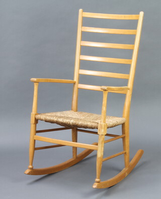 A beech framed ladder back rocking chair with woven rush seat 