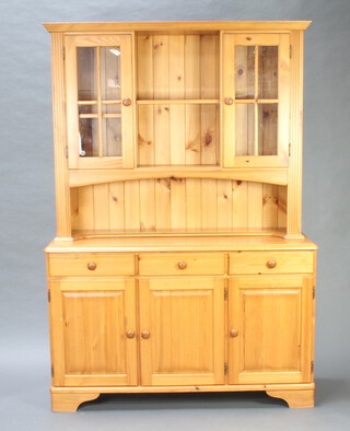 A pine dresser, the raised back fitted a recess flanked by cupboards above recess, the base fitted 3 drawers above triple cupboards and raised on bracket feet 190cm h x 131cm w x 43cm d 