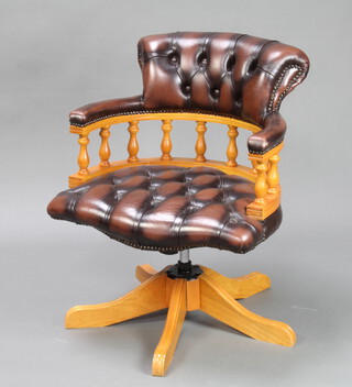 A beech framed Captain style tub back revolving office chair upholstered in buttoned brown leather 