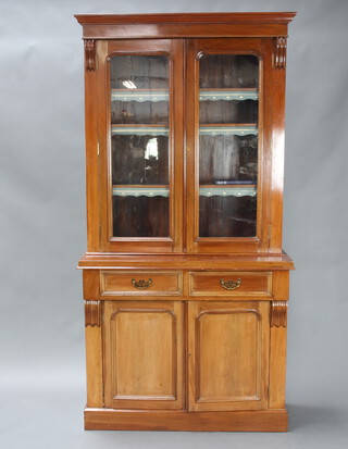 A Victorian mahogany bookcase on cabinet with moulded cornice, fitted adjustable shelves enclosed by glazed panelled doors, the base with 2 drawers above cupboards enclosed by arched panelled doors, on a platform base 210cm h x 105cm w x 43cm d 