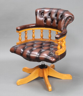 A Victorian style beech revolving captains office chair upholstered in buttoned leather 