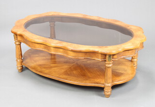 A Philadelphia style oval elm coffee table with bevelled plate panelled glass top, raised on turned supports with undertier 41cm h x 120cm l x 80cm w