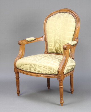 A French style carved walnut open arm salon armchair, the seat and back upholstered in floral material raised on turned and fluted supports 92cm h x 61cm w (inside measurements 50cm x 47cm)