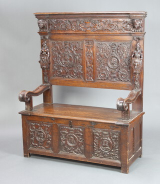 A Victorian oak settle (made up), the raised back heavily carved throughout with portrait decoration, the base formed from a carved oak coffer 150cm h x 120cm w x 50cm d (inside seat measurement 99cm w x 45cm d) 