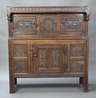 A 17th/18th Century oak court cupboard, the upper section heavily carved throughout enclosed by panelled doors, the base enclosed by panelled doors, raised on square supports, the apron marked 1668 159cm h x 146cm w x 56cm d  
