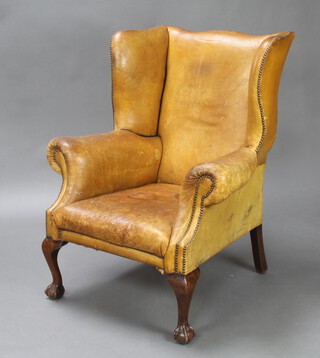 A Georgian style winged armchair upholstered in brown leather, raised on cabriole ball and claw supports 111cm h x 82cm w x 70cm d,(inside seat measurement 47cm w x 57cm d) 