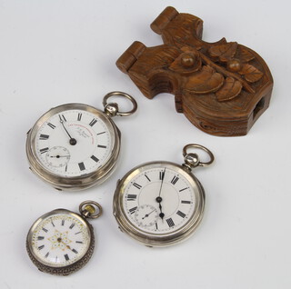 An Edwardian silver keywind pocket watch Chester 1903 50mm, a ditto Chester 1880 50mm and a lady's Edwardian fob watch together with a carved fruitwood watch hold 
