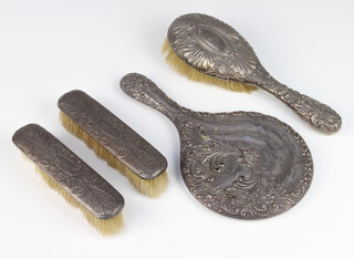 An Edwardian repousse silver hand mirror Sheffield 1910, a brush and 2 clothes brushes 