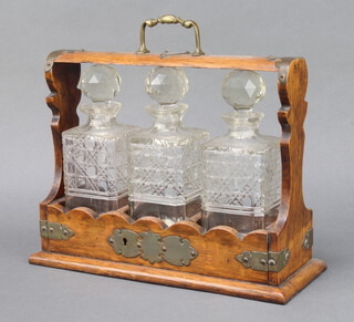 An Edwardian plated mounted oak 3 bottle tantalus with 3 decanters