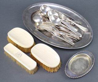 An oval plated meat dish and minor plated cutlery 