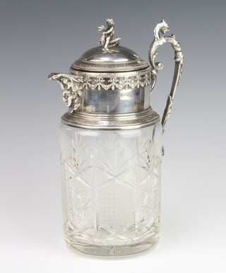 An Edwardian silver plated mounted cut glass lemonade jug the finial in the form surmounted a child riding a swan, having a mask handle with floral swags and festoons and a cut glass body 30cm h