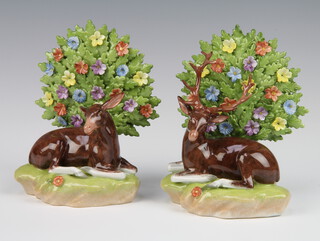 A pair of modern Dresden porcelain figures of seated deer before floral encrusted trees, raised on rocky bases 15cm  