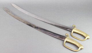 A pair of 19th Century cutlasses with 69cm polished blades, one brass grip with broad arrow mark, both with crown  