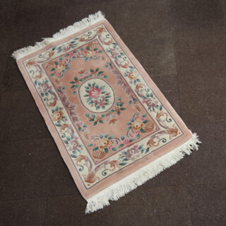 A peach ground and floral patterned Chinese rug 163cm x 92cm 