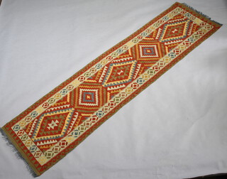 A brown and white ground Kilim runner with 5 stylised diamonds to the centre 300cm x 79cm 