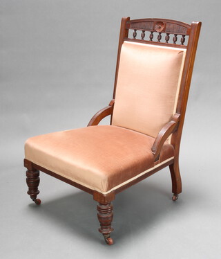 A Victorian carved walnut nursing chair upholstered in pink dralon with bobbin decoration raised on turned supports 94cm h x 50cm w x 60cm d (seat 35cm w x 54cm d)  