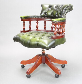 A mahogany revolving captain's/office chair upholstered in green buttoned leather with spindle decoration, raised on a tripod base 83cm h x 61cm w x 55cm d (seat 48cm w x 46cm d)