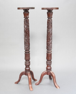 A pair of William IV carved mahogany bedpost torcheres raised on pillar and tripod bases 135cm h x 27cm diam. 