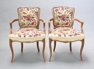 A pair of French style beech open arm chairs, the seats and backs upholstered in floral Berlin woolwork, 86cm h x 58cm w x 53cm d (seat 40cm x 46cm) 