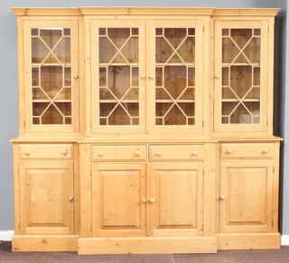 A Georgian style triple breakfront pine bookcase on cabinet, the upper section with moulded cornice fitted 3 cupboards enclosed by astragal glazed doors, the base fitted 4 short drawers above 4 cupboards enclosed by panelled doors 208cm h x 228cm w x 45cm d