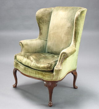A Georgian style winged armchair upholstered in green material, raised on cabriole supports 113cm h x 88cm w x 56cm d (seat 50cm x 47cm) 