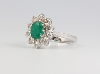 An 18ct white gold oval emerald and diamond cluster ring, the centre stone approx. 1.2ct, the brilliant cut diamonds 1ct, 5.3 grams, size N 