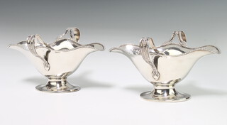 A pair of Edwardian silver double lipped sauce boats with scroll handles London 1906, 306 grams, 6cm