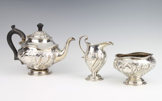 An Edwardian repousse silver 3 piece bachelor's tea set with ebony mounts and repousse floral decoration, rubbed marks, 638 grams gross