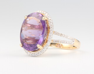 An oval amethyst and diamond cluster ring, the centre stone approx. 6.92ct surrounded by brilliant cut diamonds and diamonds to the shoulders approx. 0.3ct, 4.9 grams, size N 