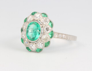 A platinum oval emerald and diamond cluster ring, the centre emerald approx. 0.79ct surrounded by brilliant cut diamonds approx. 0.66ct and emeralds 0.25ct, the diamonds to the shoulders 0.06ct, size N 1/2, 4.8 grams