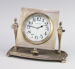 An Edwardian Waltham bedroom timepiece contained in a square silver easel frame raised on bun feet 8cm x 11cm x 5cm  
