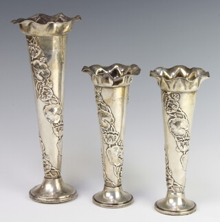 A Victorian embossed trumpet shaped silver specimen vase raised on a circular base 27cm x 7cm, marks rubbed, together with a ditto pair 20cm x 6cm marks rubbed, lead weighted