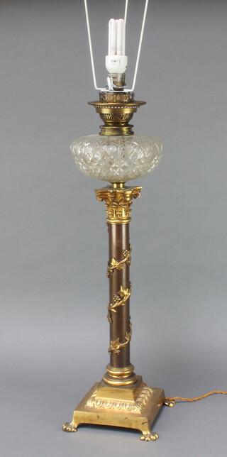 A cut glass oil lamp reservoir raised on a gilt metal ivy clad column with Corinthian capital and square base on paw feet, converted to an electric table lamp  65cm h x 19cm x 19cm 