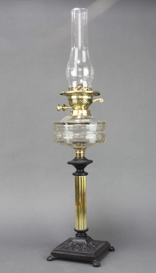 A Victorian faceted glass oil lamp reservoir, raised on a reeded brass and cast iron base complete with clear glass shade, the burner buttons with globe mark 71cm h x 16cm 