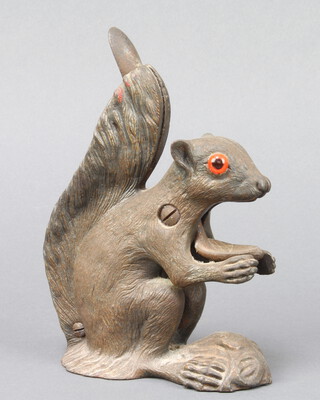 A cast metal nut cracker in the form of a seated squirrel with glass eyes 18cm h x 6cm x 13cm 