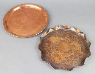 A Newlyn style circular planished copper tray with floral decoration 2cm x 29cm together with a circular plain copper tray 2cm x 28cm 