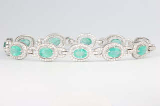 An 18ct white gold oval emerald and diamond cluster bracelet, the emeralds 7.12ct, diamonds 1.59ct, 17 grams, 19cm 