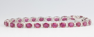 An 18ct white gold oval ruby and diamond bracelet, the diamonds approx. 0.65ct, (the rubies, treated) approx. 13.14ct, 9 grams, 18cm  