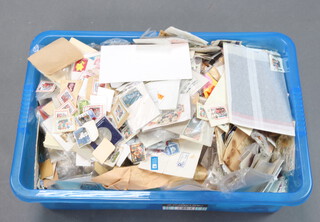 A collection of used world stamps, some on paper, some loose, contained in a large crate
