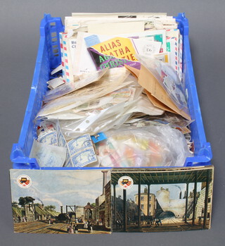 A collection of first day covers, loose world stamps contained in a blue plastic crate
