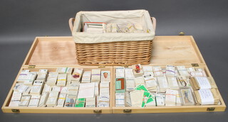 A collection of cigarette and tea cards contained in 2 shallow boxes and a rectangular twin handled basket