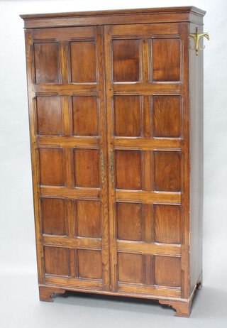 A 1930's oak hall wardrobe with moulded cornice, enclosed by panelled door, raised on a shaped base 184cm h x 104cm w x 55cm d (slight split to side) 