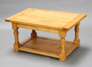 A rectangular light oak coffee table raised on turned and bock supports with undertier 46cm h x 90cm l x 59cm w