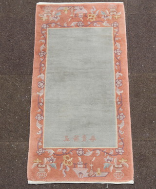 A turquoise and peach ground Chinese rug with signature to base 138cm x 69cm