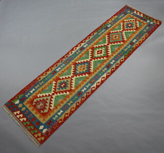 A turquoise, orange and green ground Chobi runner with 6 stylised diamonds to the centre within a 3 row border 289cm x 79cm 
