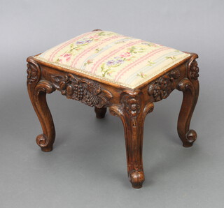 A Victorian deeply carved mahogany rectangular stool with Berlin woolwork seat and floral carving, raised on cabriole supports 36cm h x 46cm w x 37cm d 