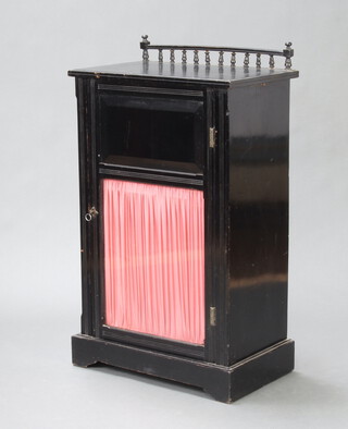 A Victorian ebonised music cabinet with raised bobbin turned back, enclosed by panelled and glazed panelled door, raised on a platform base 99cm h x 57cm w x 36cm d 